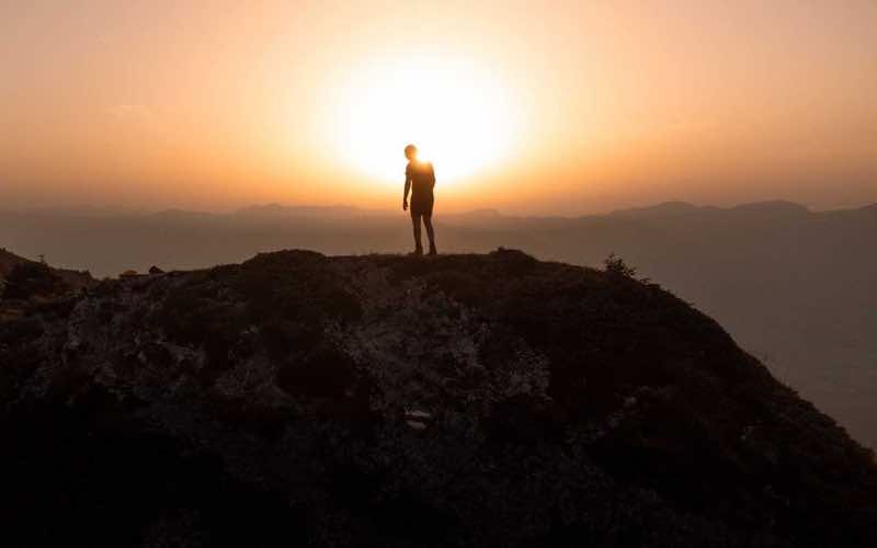 A lone figure walking a ridge at sunrise